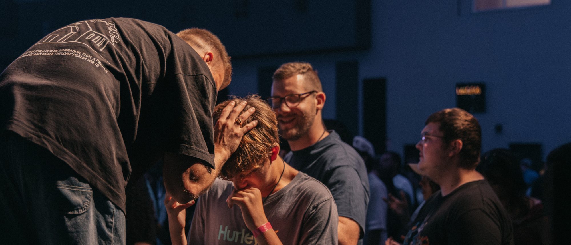 John praying over a young man during a service